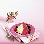 A piece of vanilla & berry iced bombe on a plate with berries
