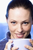 Lachende Frau hält Tasse mit einem Heissgetränk