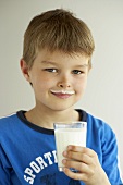 Junge mit einem Glas Milch und Milchbärtchen