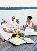 Three women picnicking by a lake