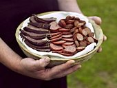 Hands holding a dish of Swedish sausage products
