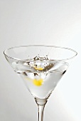 Piece of lemon peel falling into a glass of Martini
