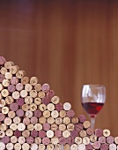 Wine corks, piled up, and a glass of red wine