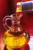 Pouring olive oil from bottle into carafe