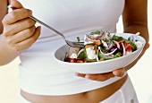 Frau hält griechischen Salat