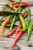 Several chili peppers on wooden background