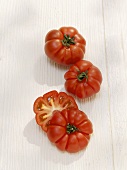Two whole and one halved beefsteak tomato
