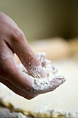 Flour in someone’s hand with pastry in background