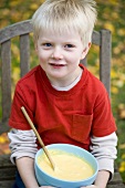 Small boy with cake mixture in a bowl