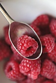 A raspberry on a spoon, several in background