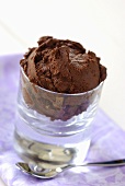 A scoop of chocolate ice cream in a glass