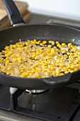 Sweating sweetcorn and onions in a frying pan