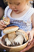 Small girl holding a bowl of ceps