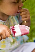 Small girl eating a raspberry ice cream lolly