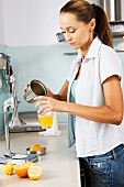 Woman pouring freshly pressed orange juice into a glass