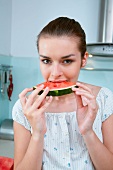 Woman biting into a piece of watermelon
