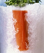 A glass of tomato juice surrounded by crushed ice