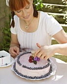Woman decorating a blueberry cake