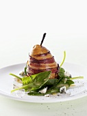 Pear wrapped in bacon on spinach salad
