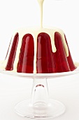 Pouring custard over cherry jelly