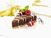 A piece of chocolate fudge cake with raspberries