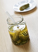 Pickled gherkins in jar with fork and on plate