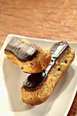 Two chocolate eclairs on plate