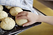 Child's hand reaching for an unbaked bread roll