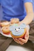 Hand holding muffin with mouse's face