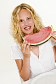 Blonde Frau isst eine Melonenspalte