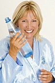 Lächelnde Frau hält eine Flasche Mineralwasser in der Hand