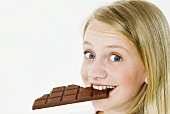 Young girl biting into a bar of chocolate