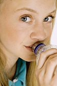 Blondes Mädchen trinkt Mineralwasser aus der Plastikflasche
