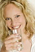 Junge Frau hält ein Glas Wasser in der Hand