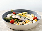 Stuffed fish with garlic and vegetables in a baking dish