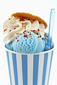Blue ice cream in tub with sprinkles and plastic spoon