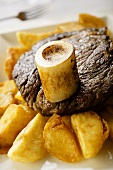 Rib eye steak with potato wedges and marrow bone