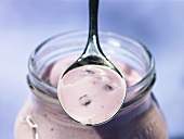 A spoonful of cherry yoghurt on a yoghurt jar