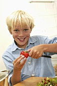 Blonder Junge beim Erdbeeren putzen