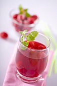A glass of raspberry juice with raspberries and lemon balm