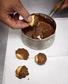Dipping piped biscuits in melted chocolate