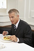 Mann in schwarzem Anzug beim Essen in einem Restaurant