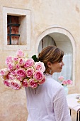 A woman carrying a bunch of roses to a garden table