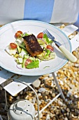 Gebratener Alaska-Seelachs mit Salat auf Teller am Strand