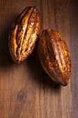 Two cocoa beans on a wooden surface
