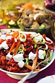 A salad with red pasta, vegetables and cream cheese