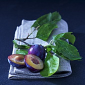 Plums with leaves on a linen cloth