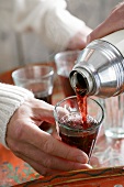 Mulled wine being poured from a thermos flask into a glass