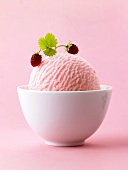 Scoop of strawberry ice cream with wild strawberries in white bowl