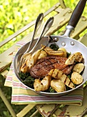 Duck breast with grilled pears in a frying pan out of doors